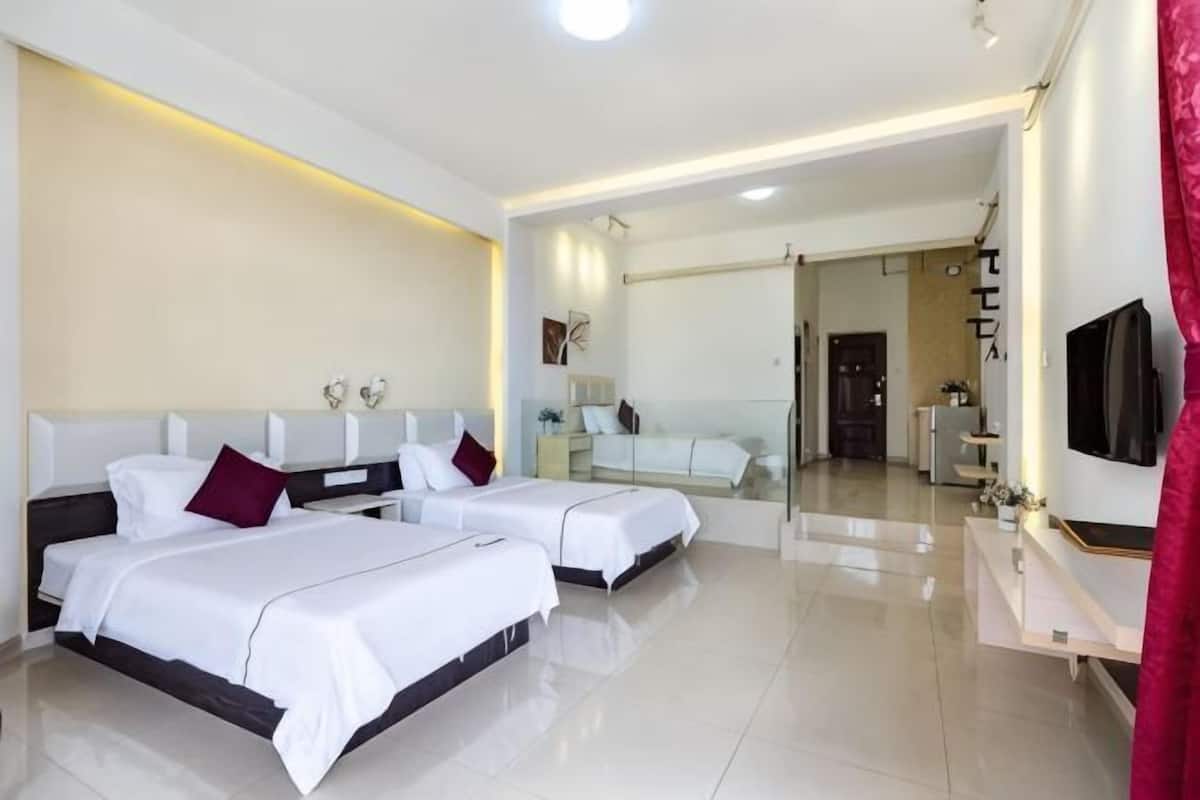 Una habitación de hotel con dos camas, un televisor, un espejo y un mueble para televisión.