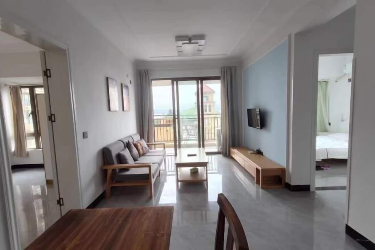 Una sala de estar moderna con un sofá, una mesa de centro de madera y un televisor montado en la pared.