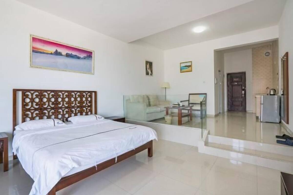 Habitación de hotel con cama, escritorio, silla, televisor y un cuadro en la pared.