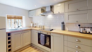 A modern kitchen with a built-in oven, a stovetop, and a window with blinds.
