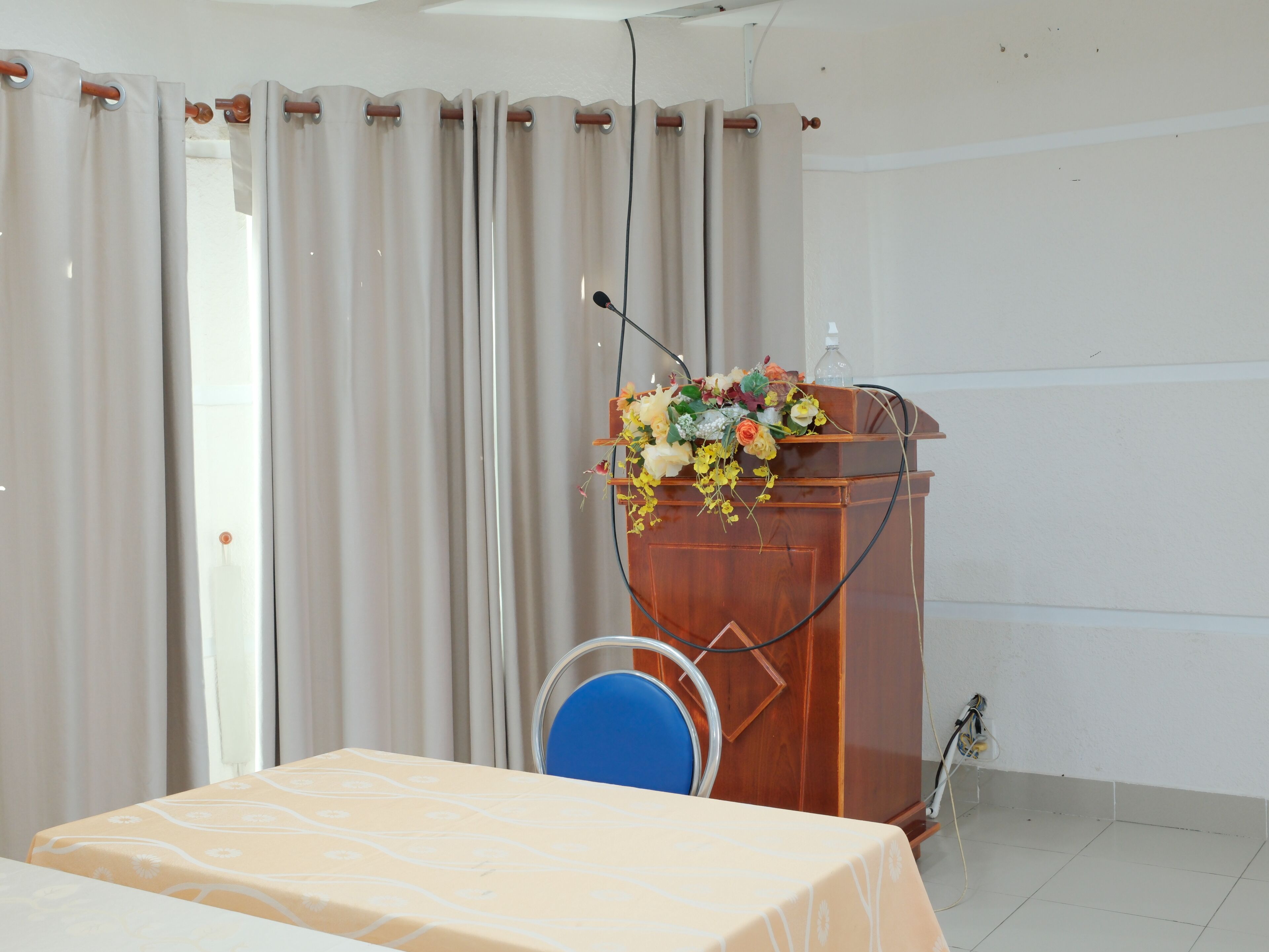 A conference room with a wooden podium, a table, and curtains.