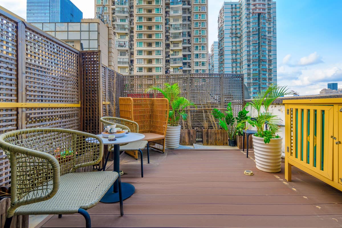 A rooftop terrace with wicker furniture, potted plants, and a yellow cabinet.