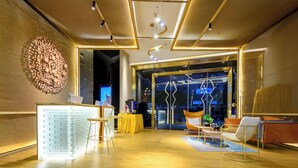 Eine moderne Lobby mit einer Rezeption, einer Sitzecke und einer großen Glasdoor, die nach draußen führt.