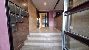 Un passadís amb armaris i una escala que porta a un ascensor.