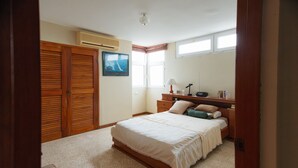 Un dormitorio con una cama grande, un armario de madera y un escritorio con una lámpara.