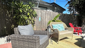 A wicker patio furniture set with cushions, a small table, and a lantern. - Mango Beach Retreat (Lake Worth)