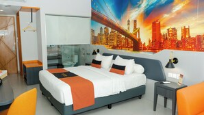 A modern hotel room with a large bed, a desk, and a chair. There is a cityscape painting on the wall and a window with a view of the city. - Azana Style Hotel Tulungagung (Tulungagung)