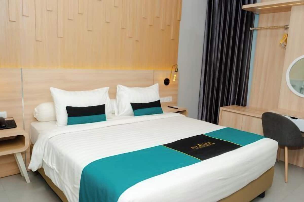 A modern hotel room with a bed, bedside tables, a desk, and a mirror.