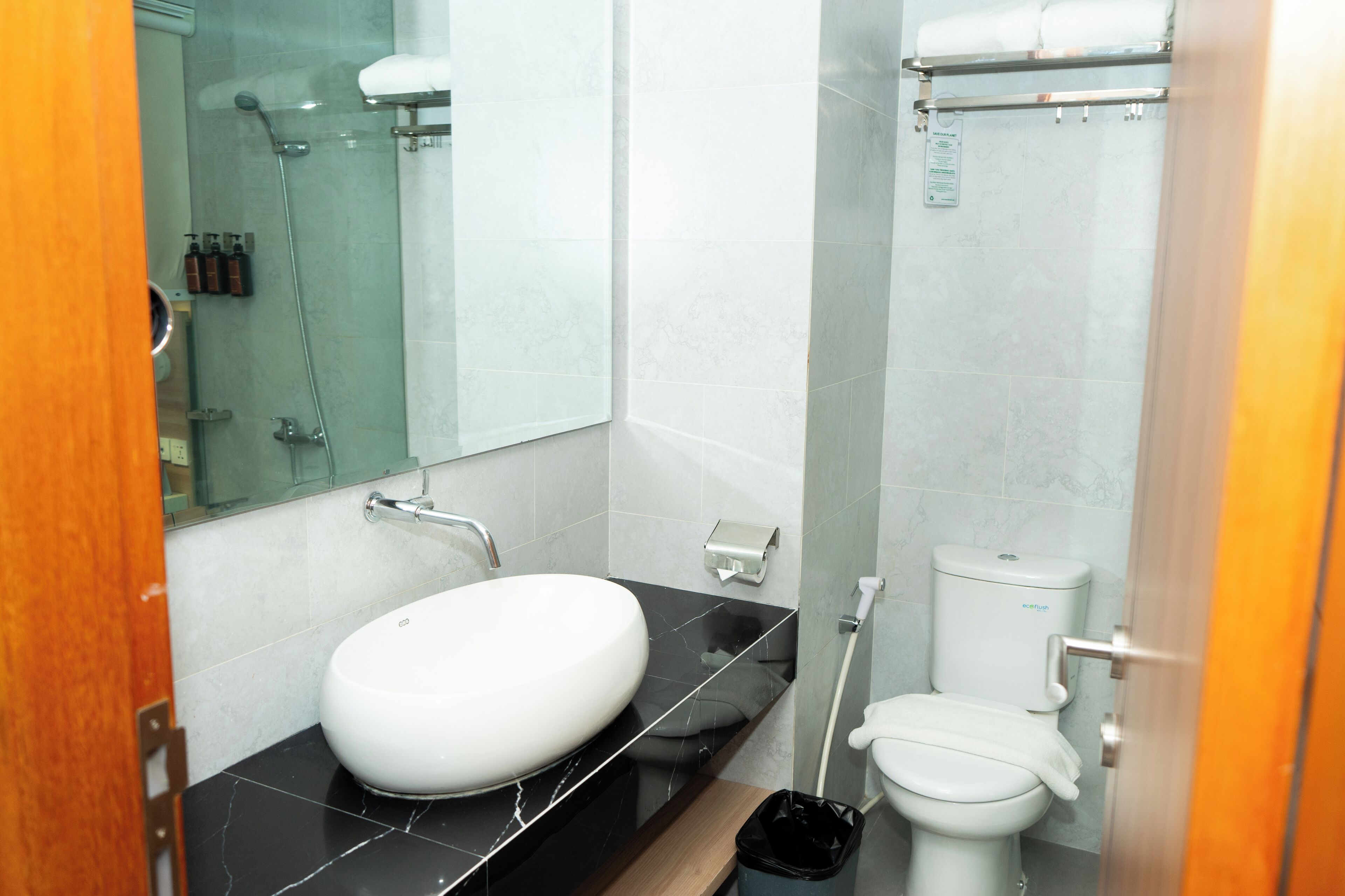 Un bagno moderno con lavandino bianco, piano di lavoro nero e box doccia in vetro.