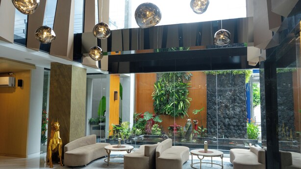 A modern lobby with a seating area, a large glass wall, and a waterfall feature. - Azana Style Hotel Tulungagung (Tulungagung)