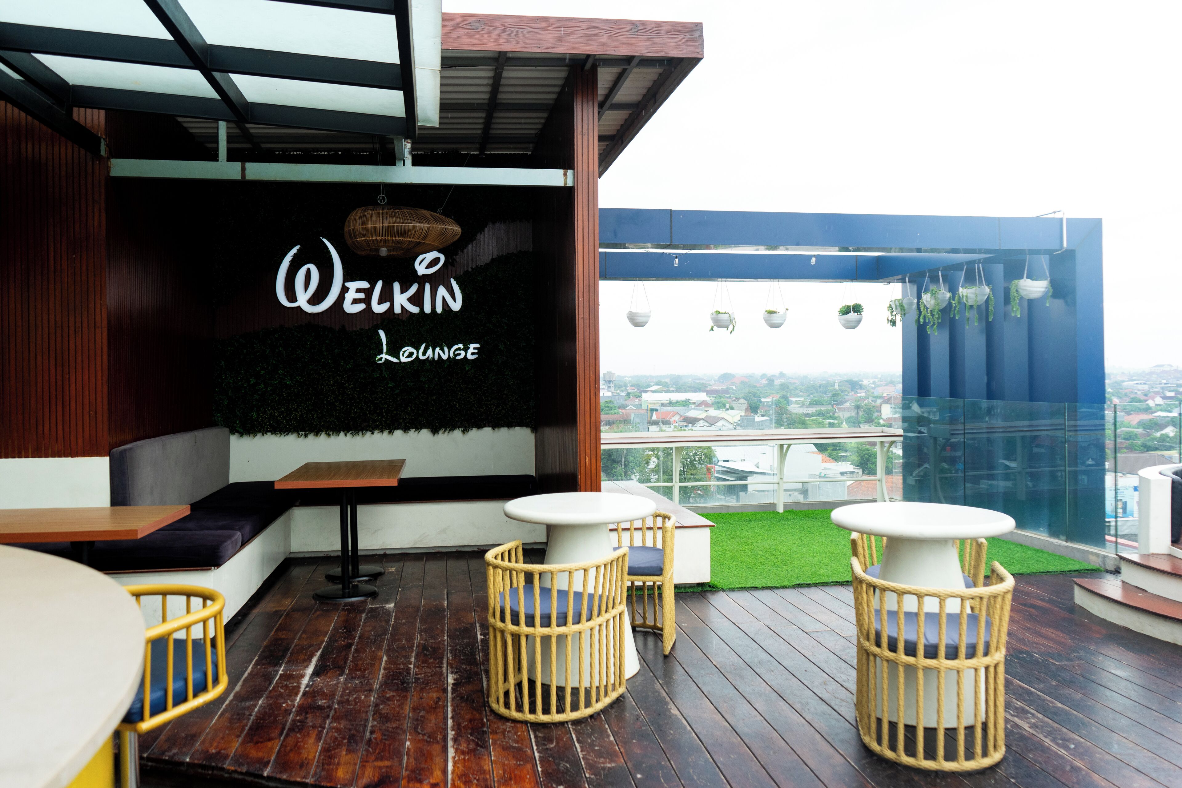Una zona de estar acogedora con un cartel que dice "Welkin Lounge", con muebles de madera y vistas a la ciudad.