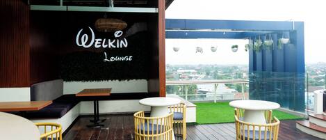Una zona de estar acogedora con un cartel que dice "Welkin Lounge", con muebles de madera y vistas a la ciudad.