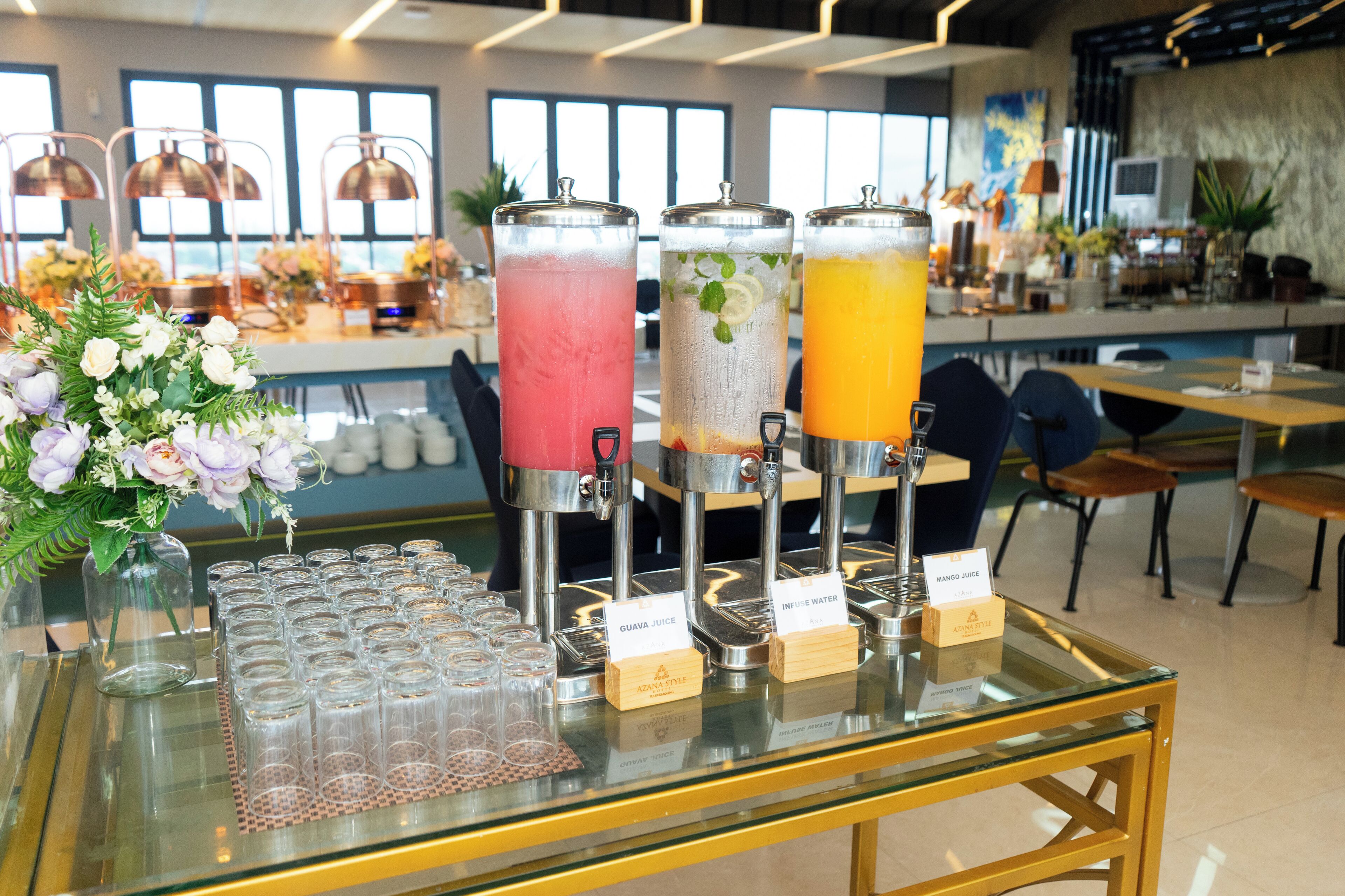 A beverage station with three dispensers labeled 'Guava Juice', 'Infused Water', and 'Mango Juice'.