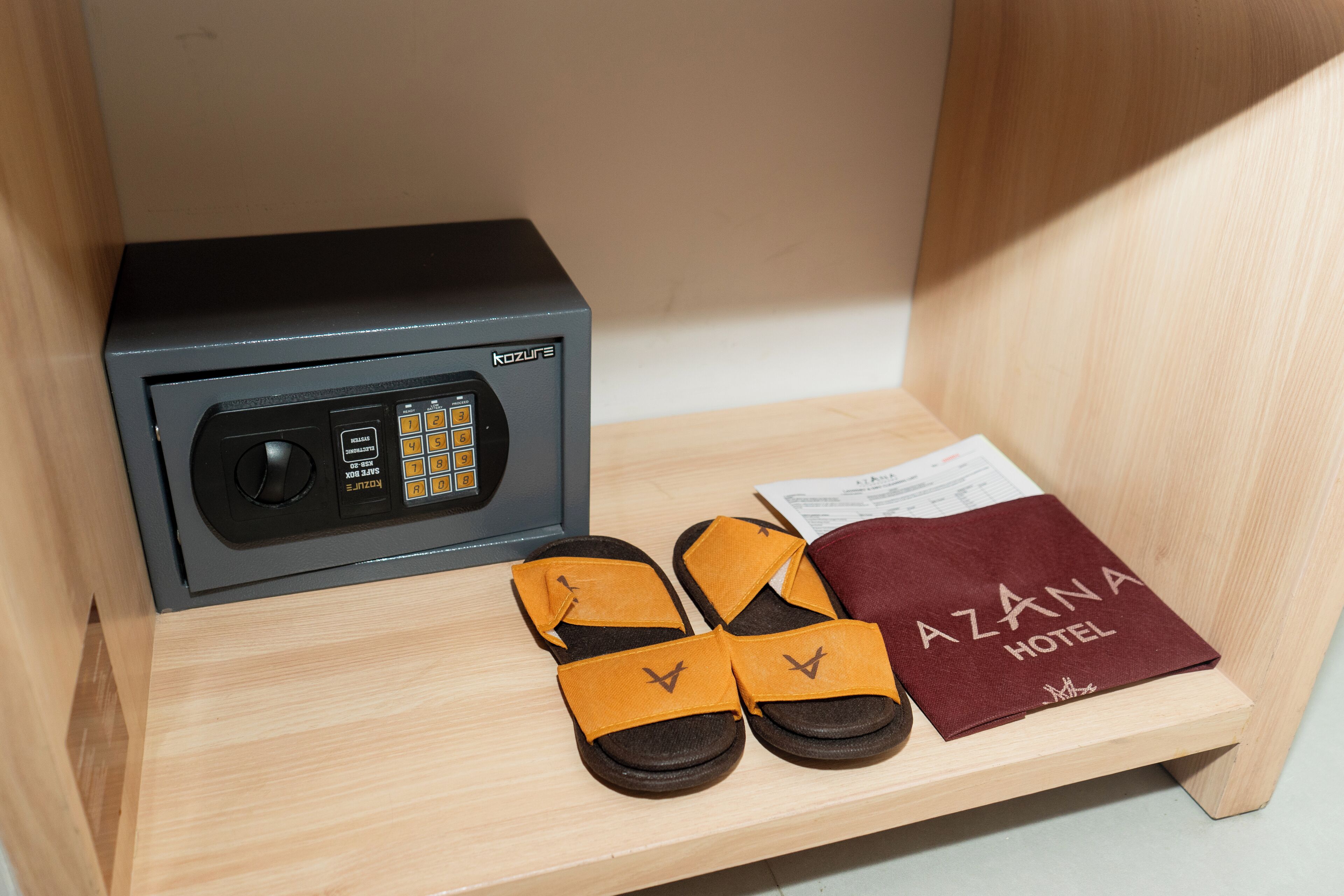 A minibar with a minibar fridge, a pair of slippers, and a hotel brochure.