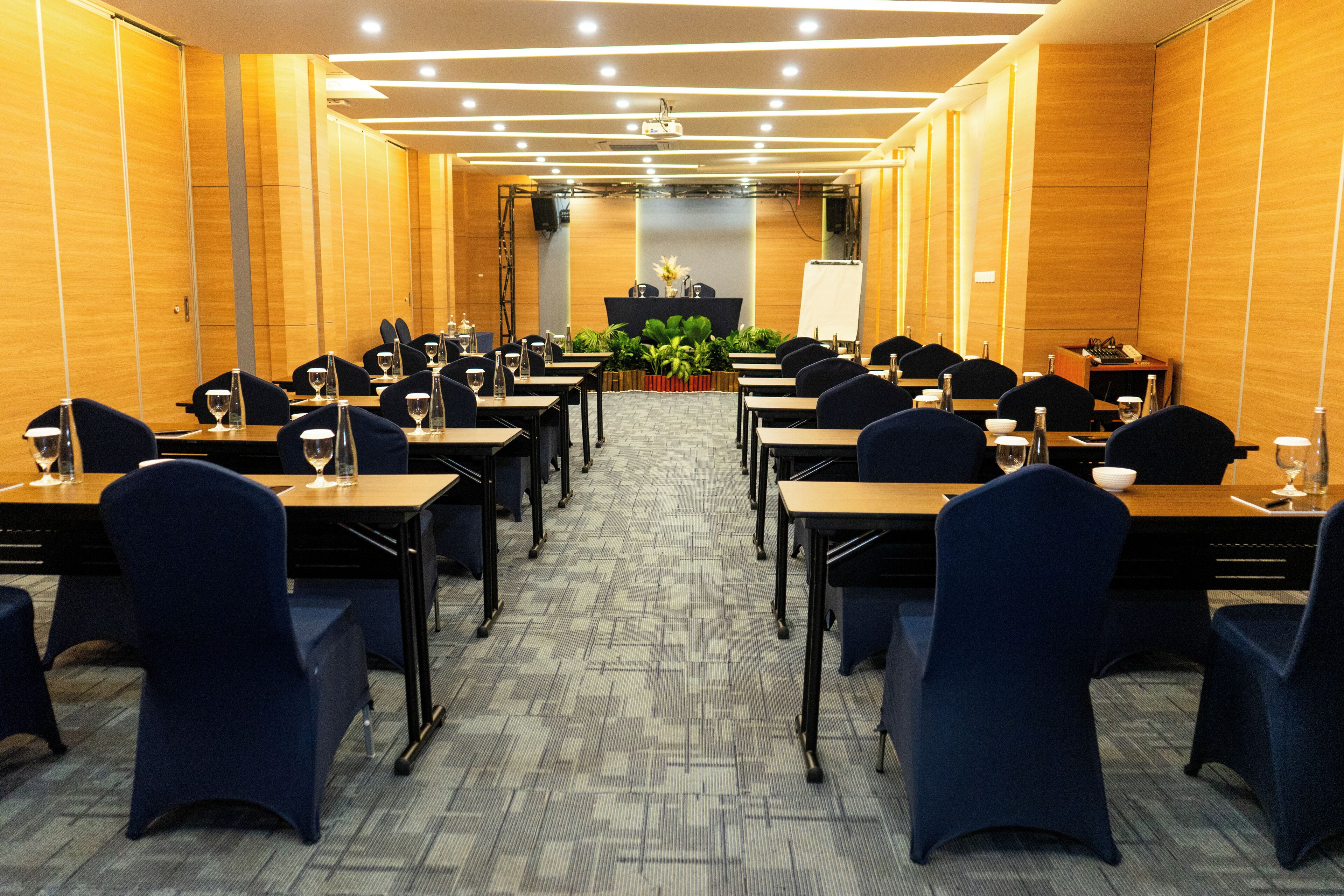 Uma sala de conferências com mesas, cadeiras, um pódio e piso coberto de carpete.