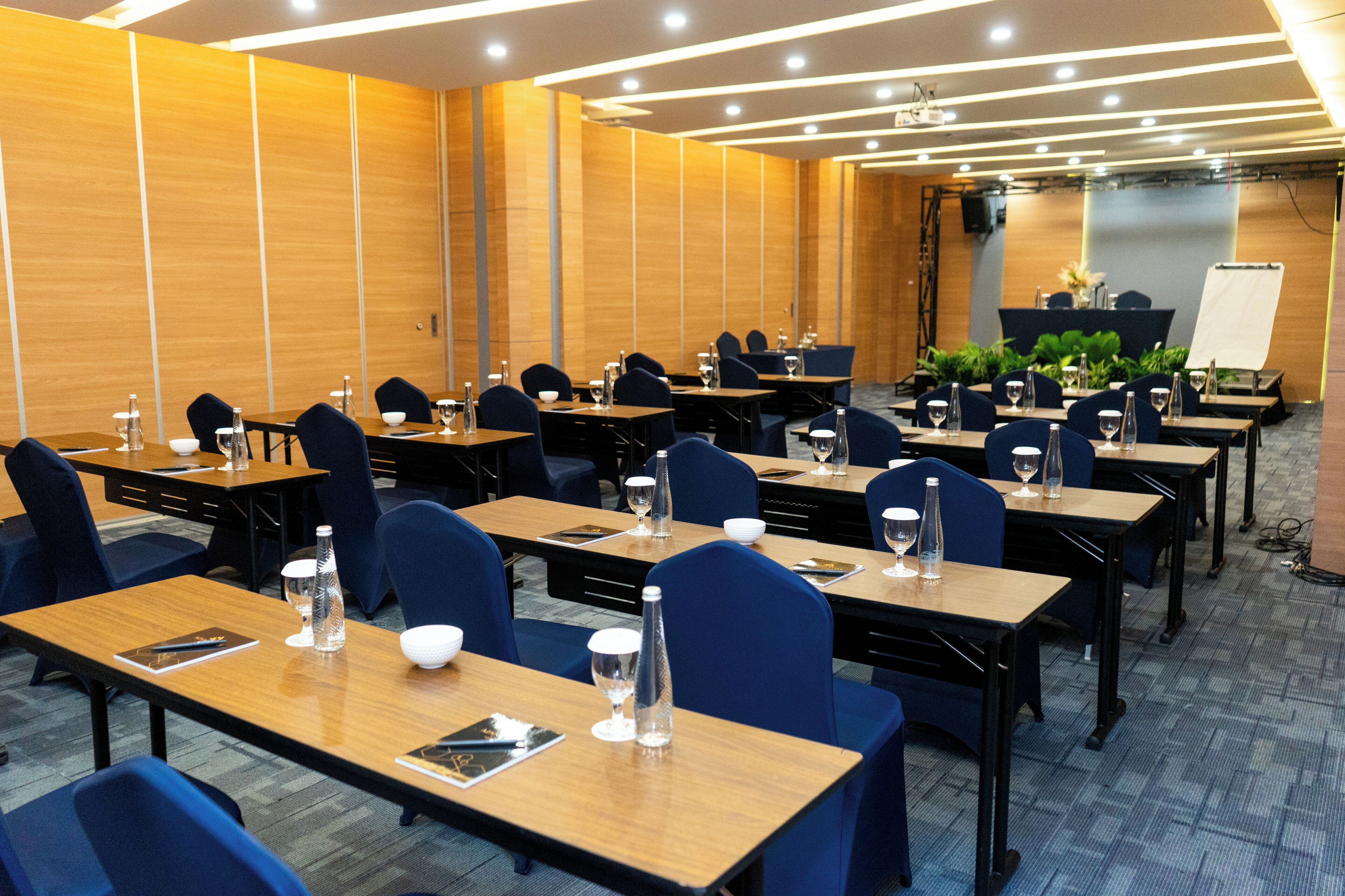 A conference room with multiple tables, chairs, and a stage area.