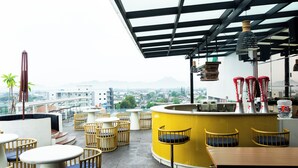A rooftop bar with yellow and white furniture, a bar counter, and a view of the cityscape. - Azana Style Hotel Tulungagung (Tulungagung)