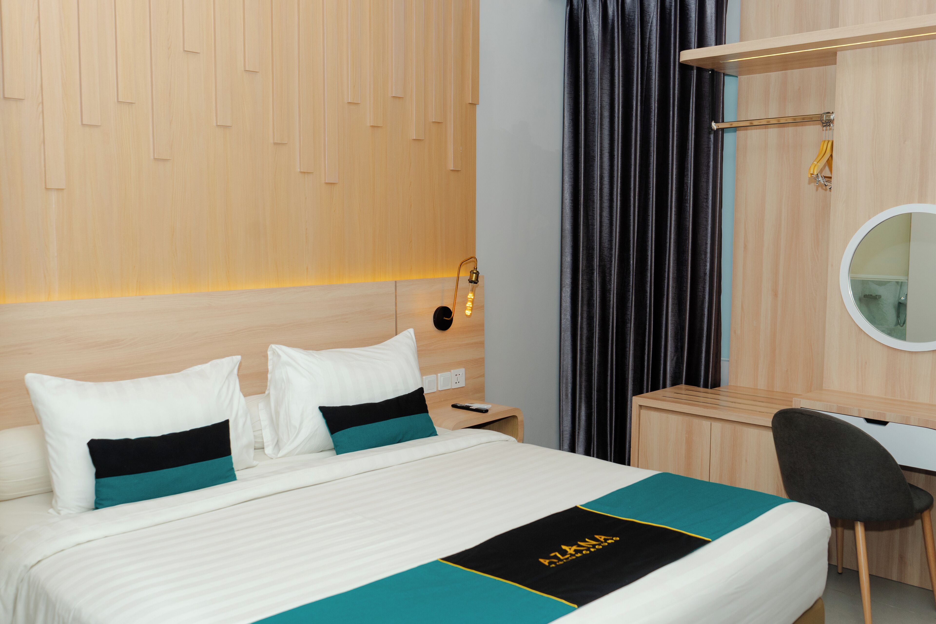 Habitació d'hotel amb un llit, escriptori, cadira, mirall i armari.