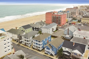 A coastal residential area with a variety of buildings, including multi-story structures and single-family homes, adjacent to a beach.