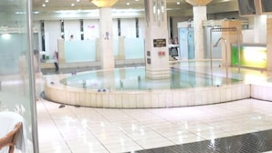 En stor indendørs swimmingpool med flisegulv, omgivet af søjler og en glasvæg.