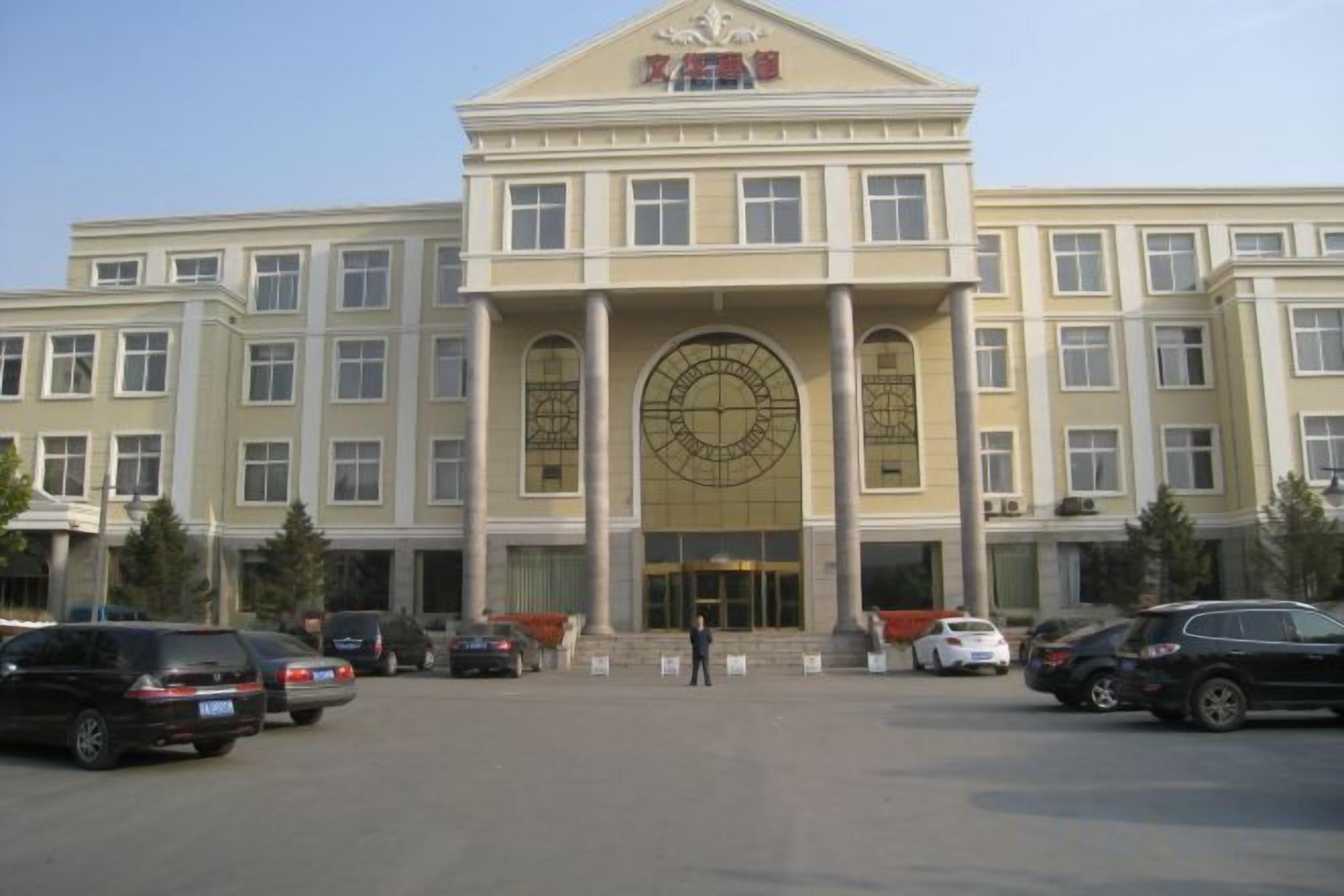 A large building with a central entrance, multiple windows, and a large circular design on the facade.