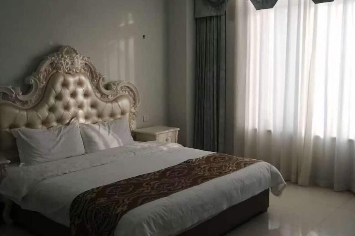 Un dormitorio con una cama grande, una mesita de noche y una ventana con cortinas.