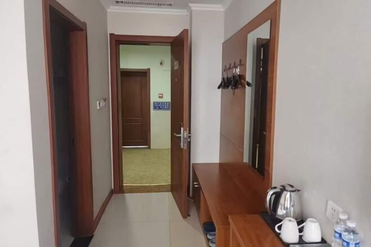 Un pasillo con un banco de madera, un perchero y una cafetera.