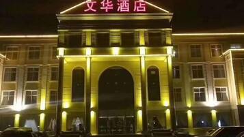 A hotel entrance with a prominent archway and illuminated signage.