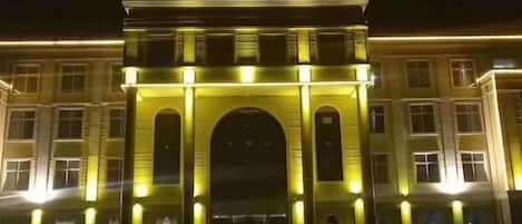 Entrada de hotel con un arco destacado y señalización iluminada.
