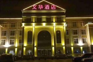 L'entrée d'un hôtel, avec une arche imposante et une enseigne lumineuse.
