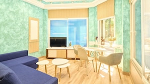 A modern living room with a sofa, a TV, a dining table with chairs, and a window with blinds. - GuestReady - Bright and Cozy studio in Salamanca (Salamanca)