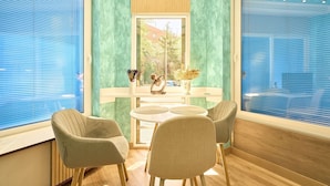 A room with a round table, two chairs, a window with blinds, and a view of greenery outside. - GuestReady - Bright and Cozy studio in Salamanca (Salamanca)