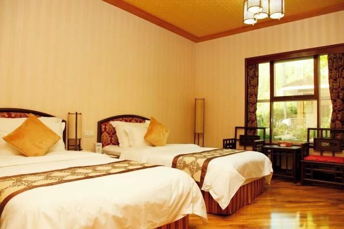 A hotel room with two beds, a desk, and a chair.