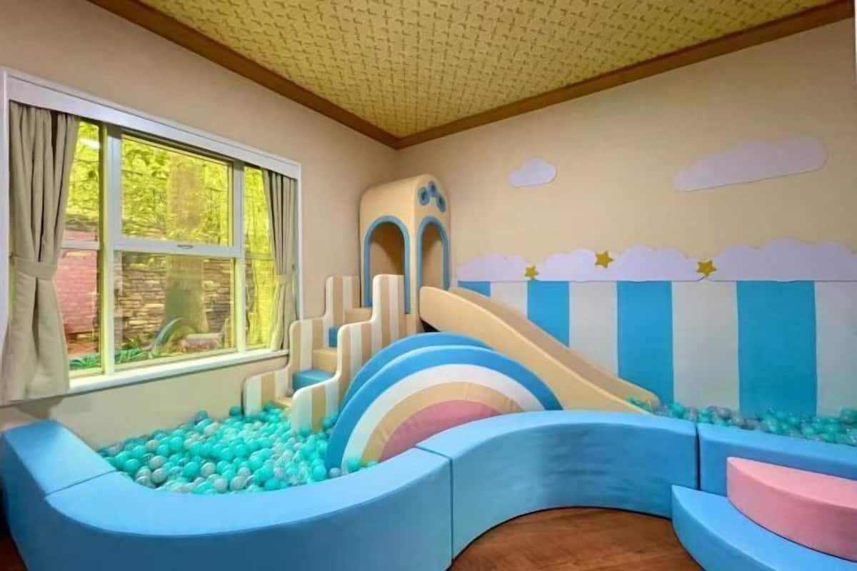 A children's play area with a ball pit, slides, and a slide with a rainbow design.