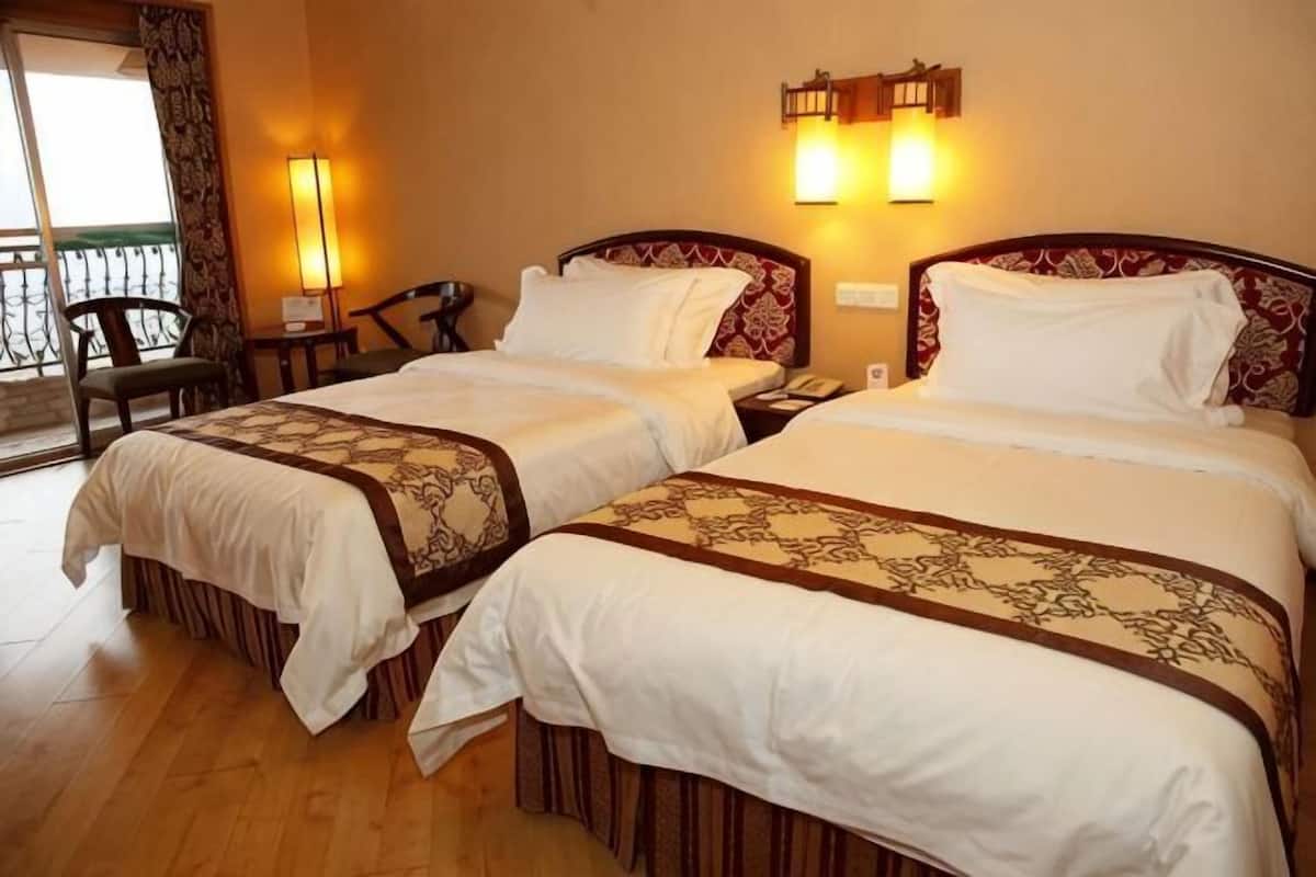 A hotel room with two beds, a balcony, and a chair.