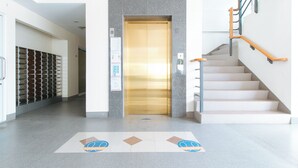 A hotel lobby with a staircase, a row of lockers, and a carpet with a logo. - Reddoorz Plus @ Alpina Heights Paranaque (Parañaque)
