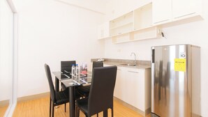 A compact kitchen with a stainless steel refrigerator, a dining table with chairs, and a countertop with a sink. - Reddoorz Plus @ Alpina Heights Paranaque (Parañaque)
