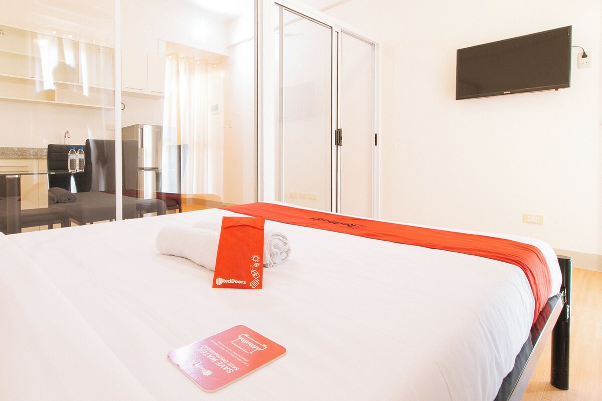 Habitación de hotel con cama, escritorio, silla, televisor de pantalla plana y cocina.
