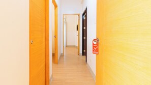 A hallway with wooden doors, a fire alarm, and a sign indicating a makeup room. - Reddoorz Plus @ Alpina Heights Paranaque (Parañaque)