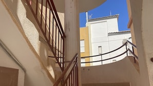 Un escalier avec des rampes en bois et une vue sur les bâtiments adjacents.