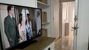 Un téléviseur posé sur un meuble en bois dans un couloir, le sol étant recouvert de carreaux décoratifs.