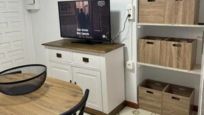 Une cuisine de taille réduite avec une table en bois, des chaises, un téléviseur et des placards intégrés.
