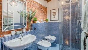 A bathroom with a large mirror, a sink, a bidet, and a shower enclosure. - La Dorina Penthouse in Lucca (Lucca)