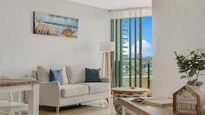 A modern living room with a grey sofa, a small round table, and a painting on the wall. - Boasting coveted north facing views and an unrivalled coastal lifestyle. (Tweed)