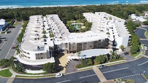 A modern hotel with a curved layout, multiple balconies, and a pool area. - Boasting coveted north facing views and an unrivalled coastal lifestyle. (Tweed)