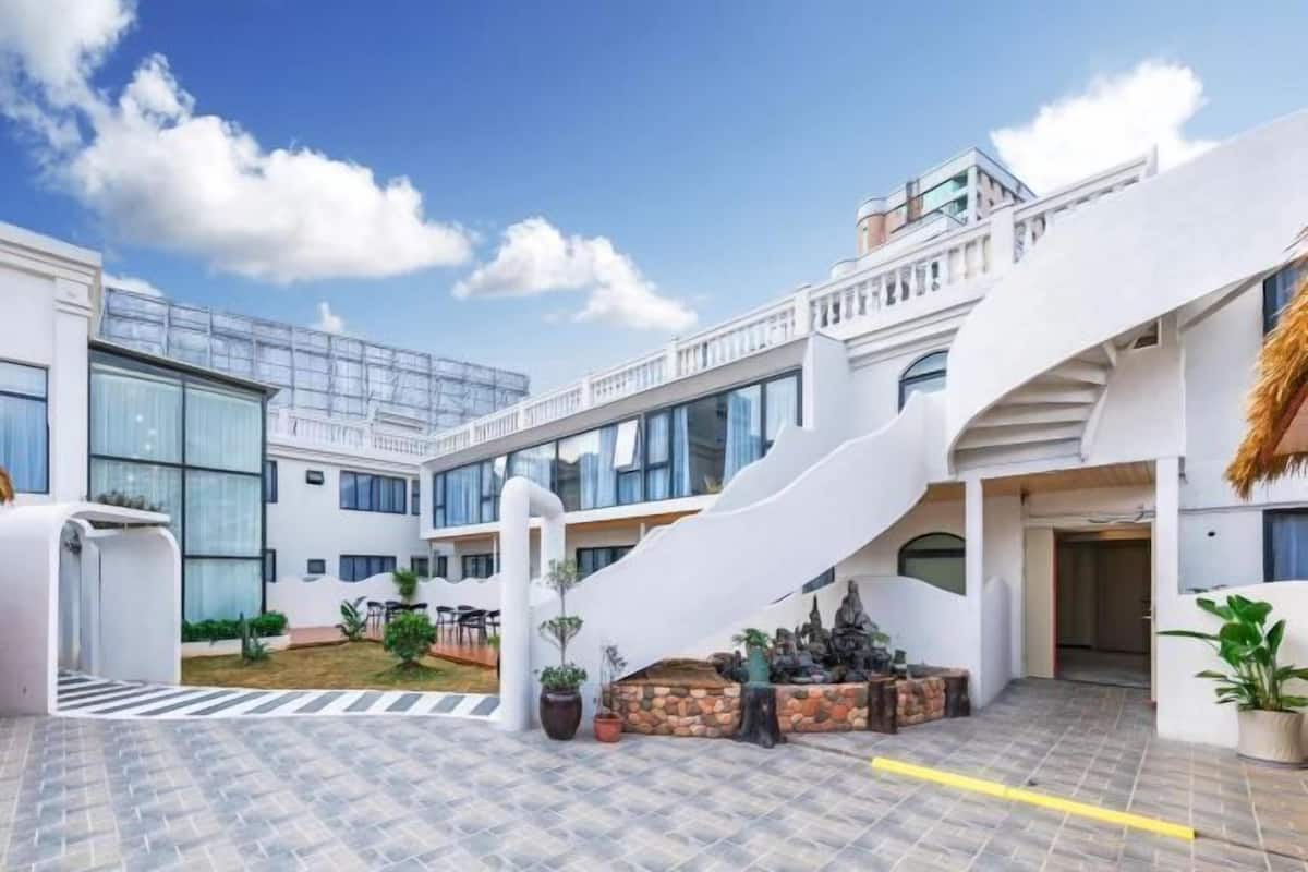 A modern building with a central staircase, outdoor seating, and a clear sky.