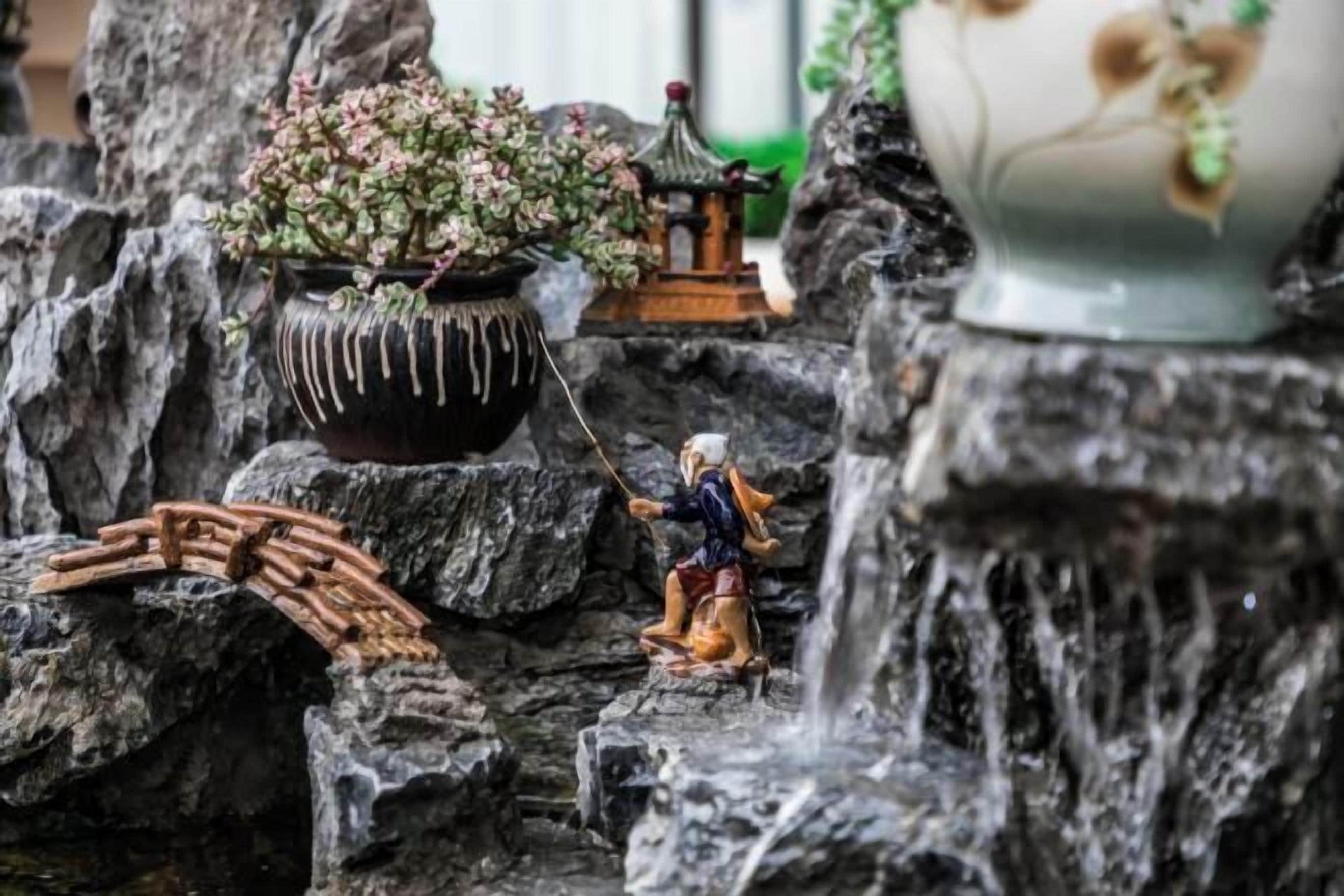 A miniature garden with a bridge, a statue, and a small pagoda.