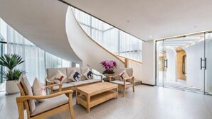 Un vestíbulo moderno con una escalera curva, un conjunto de sofás y una mesa de centro.