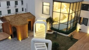 Un edificio moderno con fachada de vidrio, una estructura de techo de paja y una escalera en espiral.