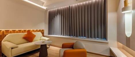 A modern hotel room with a sofa, ottoman, and a small table.